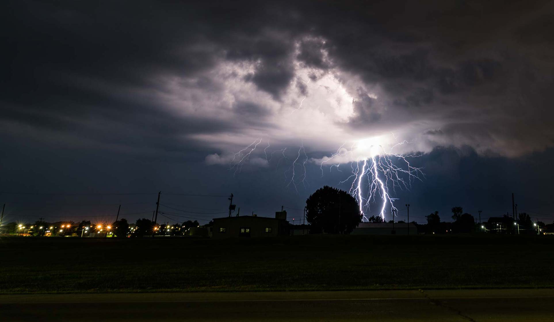 Lightning strikes at night in distance of rural Midwest town