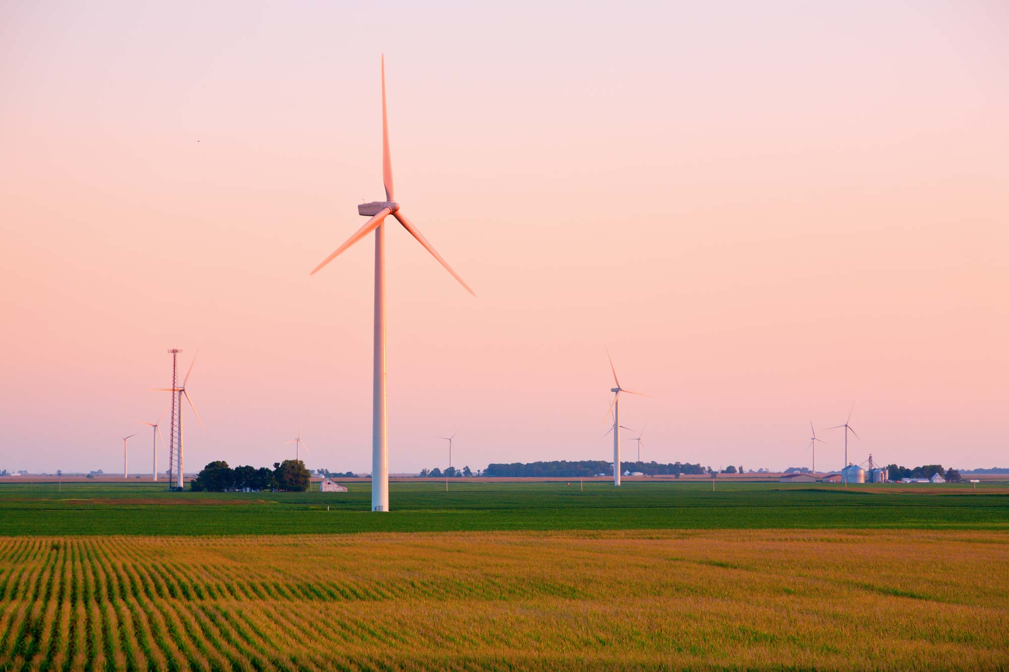 Wind turbines at sunset across Midwest agricultural landscape