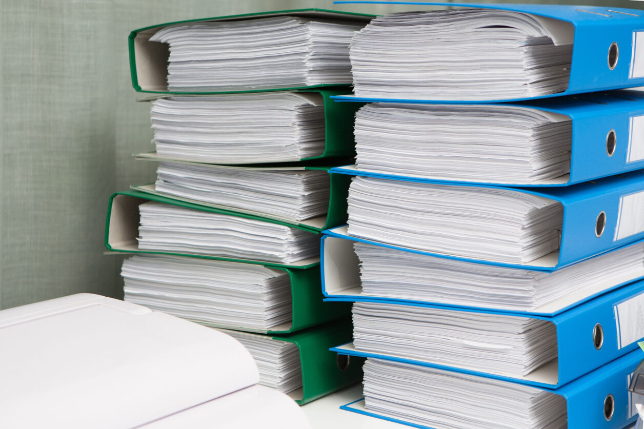 Stack of binders filled with paperwork for reliability standards